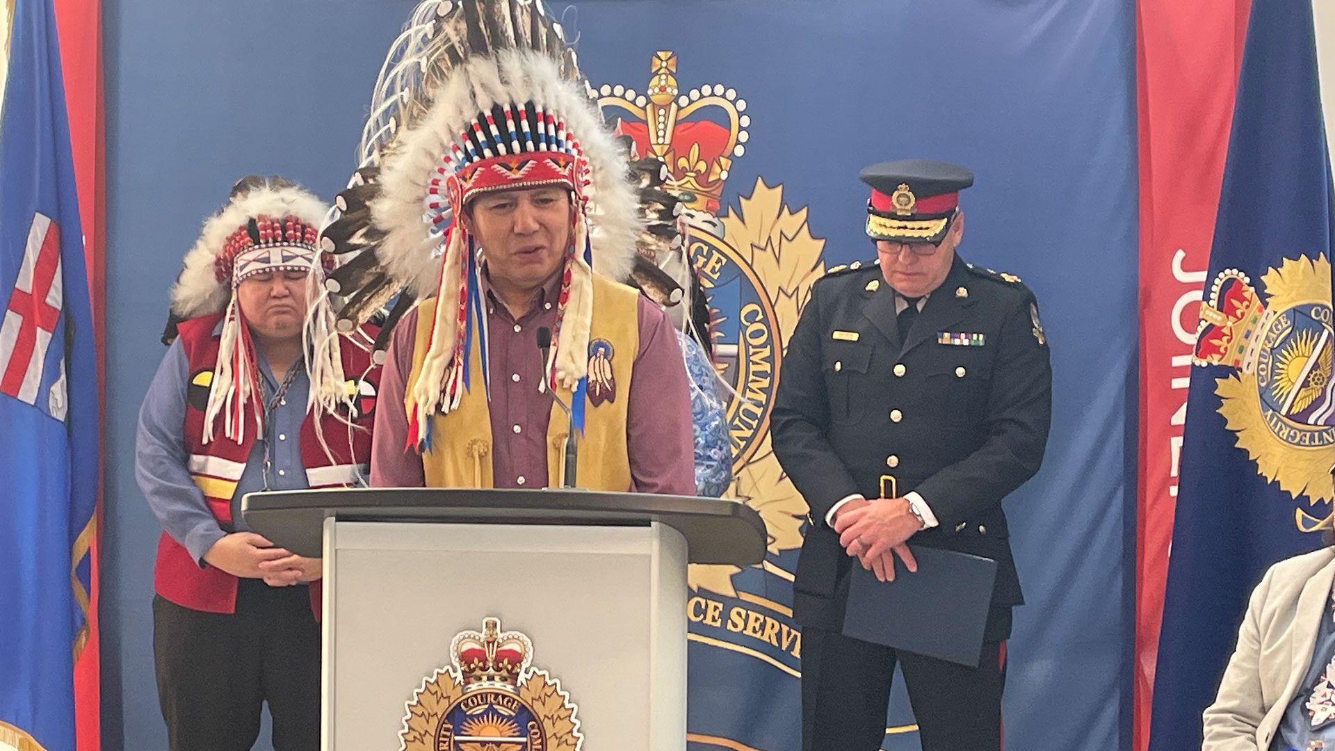 Grand Chief Arthur Noskey wearing a headdress in front of Police Chief Dale Mcphee