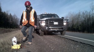 (A worker with SWN Resources Canada contractor Geokinetics walks toward a geophone on the shoulder of Hwy 11 in New Brunswick. APTN/Photo)